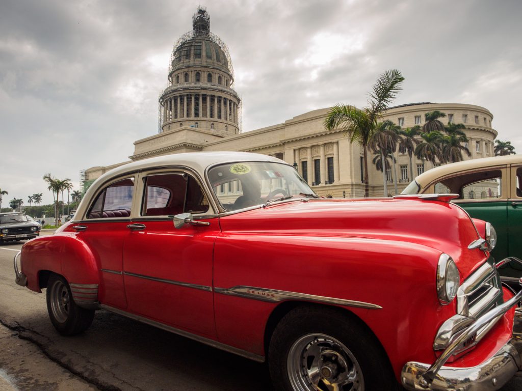 Red classic car in front of the Havana's Capitolio BY RUDY GIRON