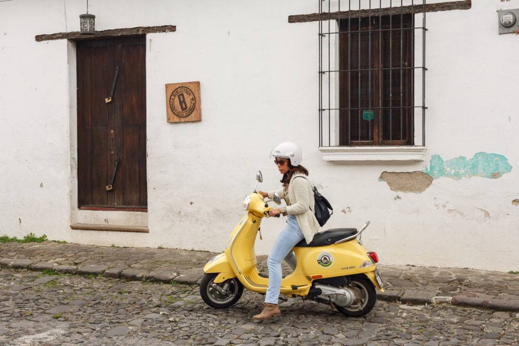 Woman on yellow scooter on the streets of Antigua Guatemala by RUDY GIRON